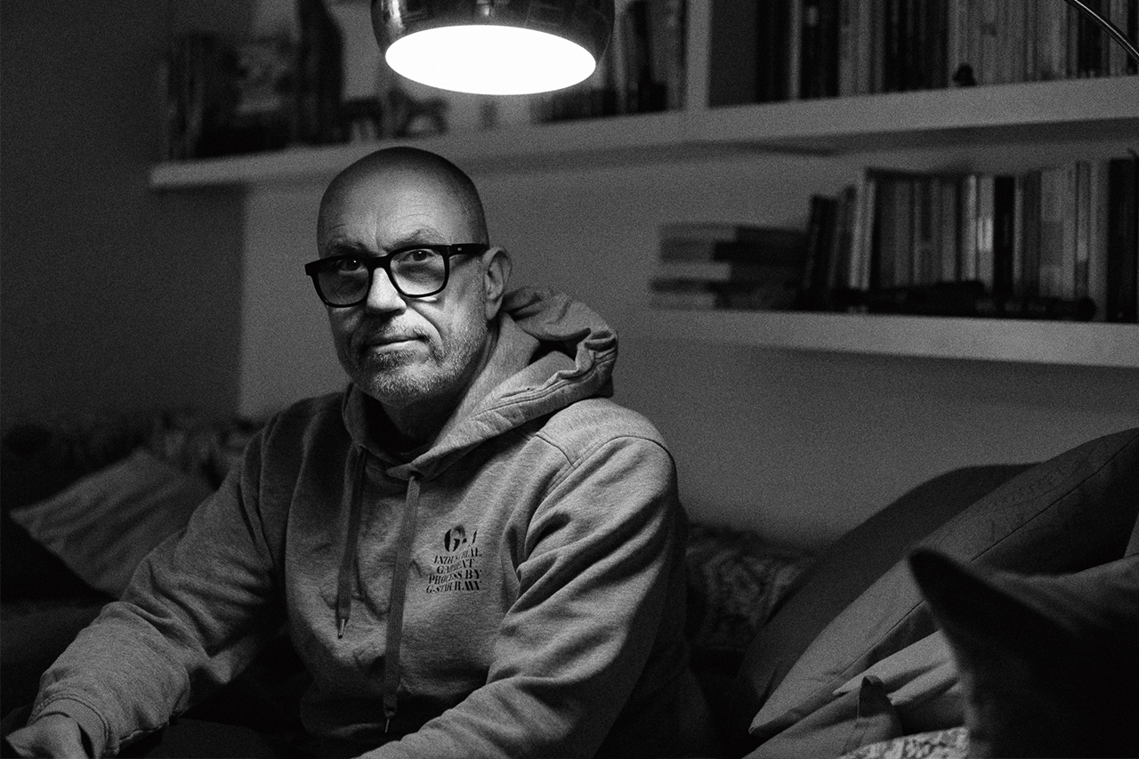 Schwarzweiß Porträt eines Mannes mit Brille im weichen Lampenlicht, intime Stimmung, Bücherregal im Hintergrund