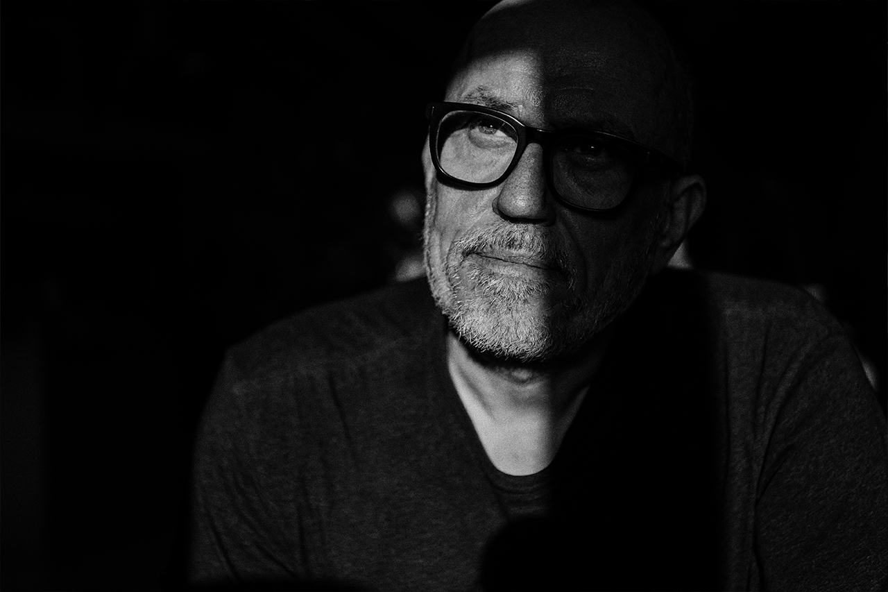 Schwarzweiß Porträt eines Mannes mit Brille im Schatten, Blick nach oben, reduzierte Bildsprache